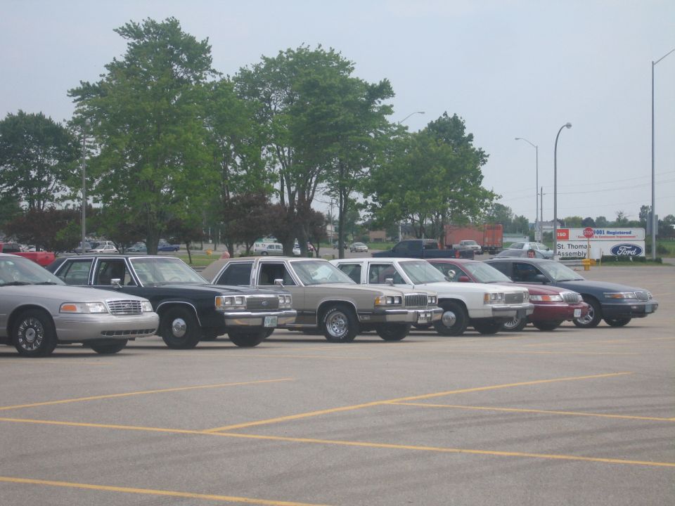 Several sedans parked in a row, including a silver Crown Victoria and a black Crown Victoria