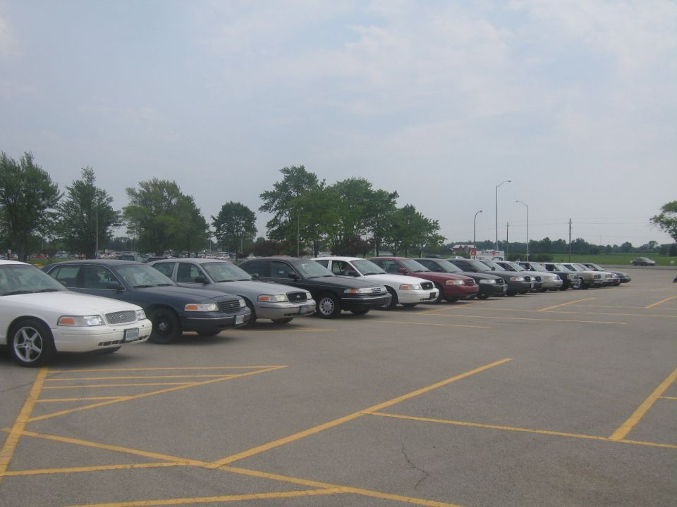 Side view of a line of white and dark police cars parked in a lot