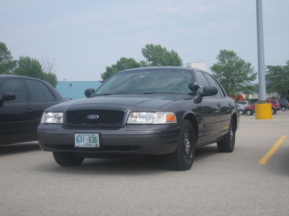 Dark gray 2001 Ford Crown Victoria police car, front view, parked in a lot