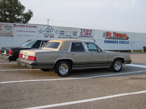 2001 Ford Crown Victoria - Photo of a tan Mercury sedan parked beside the St. Thomas Dragway signage wall.