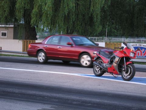 2001 Ford Crown Victoria - Photograph of a Ford sedan and motorcycle at a dragstrip, not a technical document.
