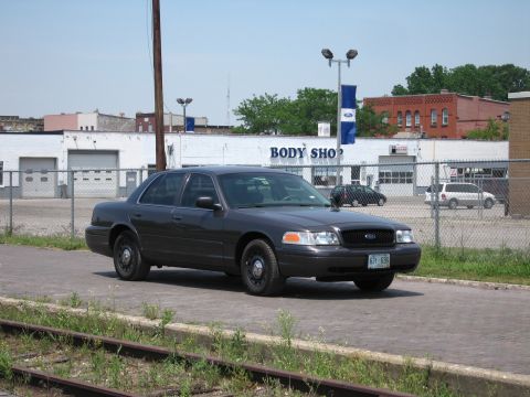 2001 Ford Crown Victoria - Photograph of a gray Ford Crown Victoria in an industrial area, not a technical document.