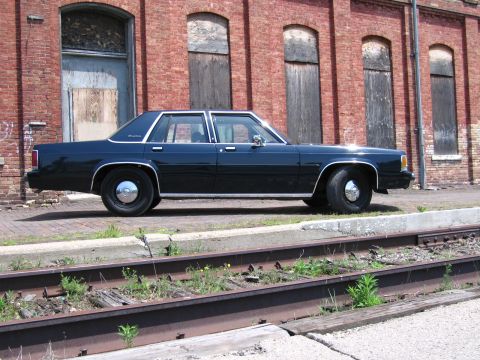 2001 Ford Crown Victoria - Photo of a dark blue Ford LTD Crown Victoria sedan parked along railroad tracks in front of a brick building.