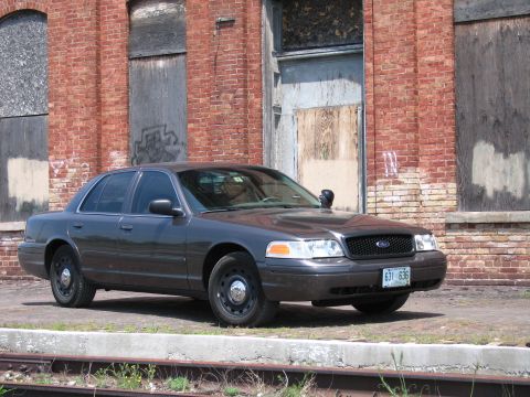 2001 Ford Crown Victoria - Photo of a gray Ford Crown Victoria sedan parked in front of an old brick warehouse.