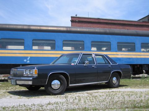 2001 Ford Crown Victoria - Side-profile photo of a black Ford LTD Crown Victoria sedan in front of a blue passenger train car.