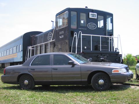 2001 Ford Crown Victoria - Photograph of a gray Ford Crown Victoria parked alongside a St. Thomas Central Railway locomotive.