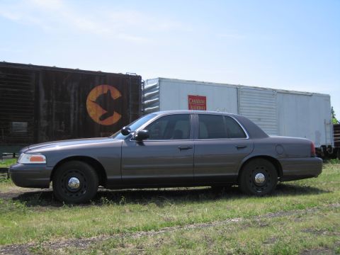 2001 Ford Crown Victoria - Photograph of a gray Ford Crown Victoria sedan in front of old railway boxcars.