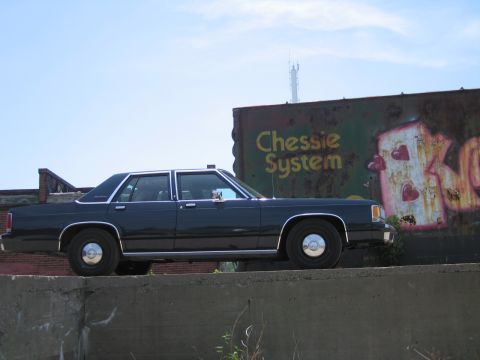 2001 Ford Crown Victoria - Photograph of a black Ford LTD Crown Victoria sedan in front of a weathered Chessie System railroad boxcar.