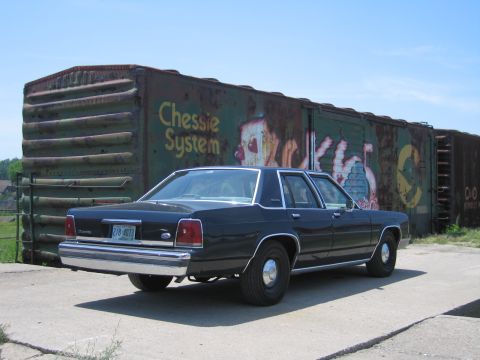 2001 Ford Crown Victoria - Photograph of a black Ford LTD Crown Victoria parked alongside a Chessie System railroad boxcar.