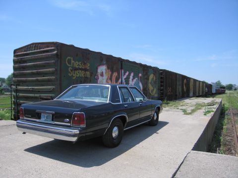 2001 Ford Crown Victoria - Photograph of a black Ford LTD Crown Victoria parked next to a string of railroad boxcars.