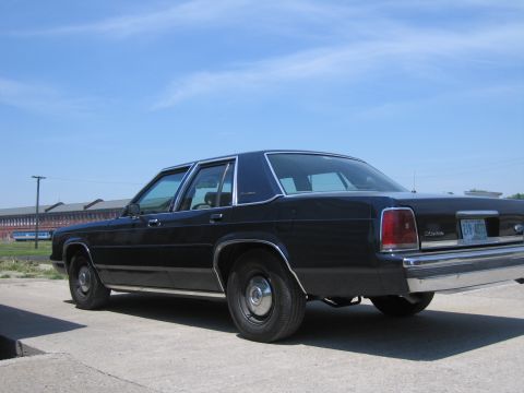 2001 Ford Crown Victoria - Photograph of a black Ford LTD Crown Victoria parked on pavement in an open railyard.