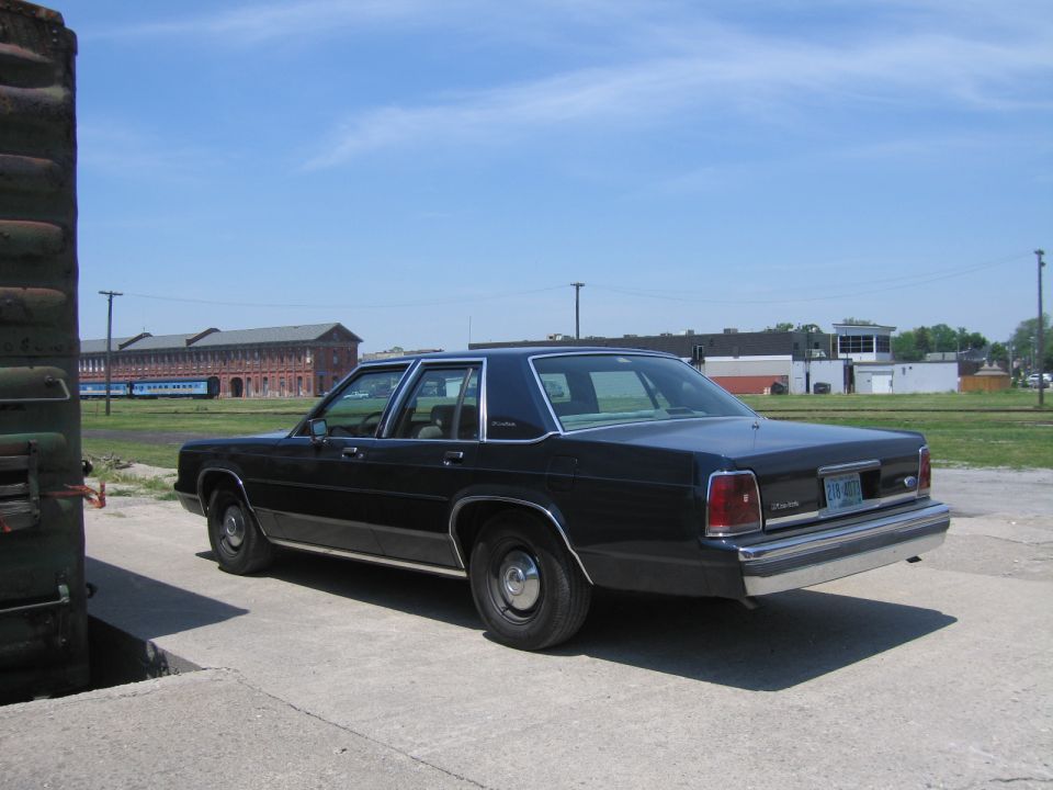Black Ford LTD Crown Victoria parked near rail equipment in a railyard