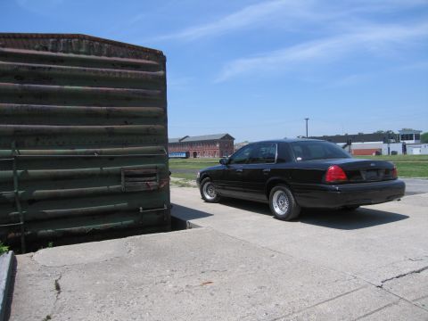 2001 Ford Crown Victoria - Photo of a black Ford Crown Victoria near a rusted boxcar, not a technical document.