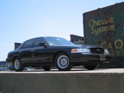2001 Ford Crown Victoria - Photo of a black Ford Crown Victoria by a Chessie System boxcar, not a technical document.