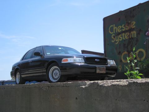 2001 Ford Crown Victoria - Photo of a black Ford Crown Victoria near a Chessie System boxcar, not a technical document.