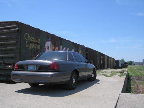 2001 Ford Crown Victoria - Photo of a gray Ford Crown Victoria beside a line of boxcars, not a technical document.