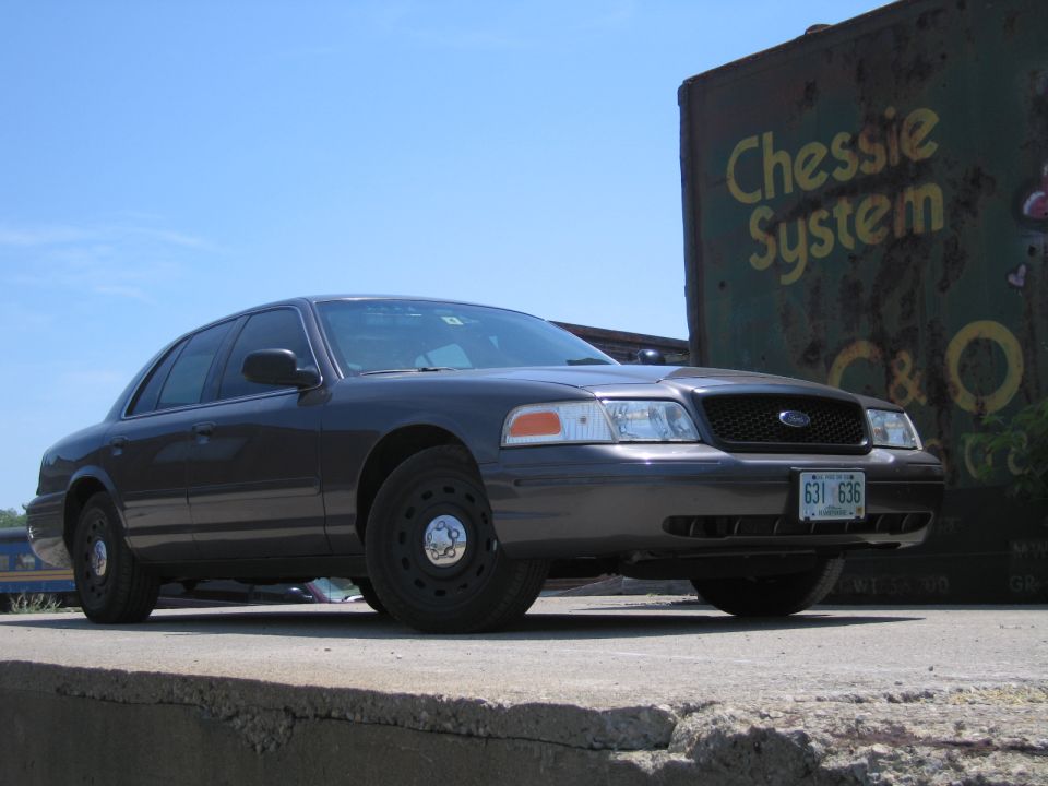 Dark sedan parked outside, front end visible. Looks like a 2001 Ford Crown Victoria