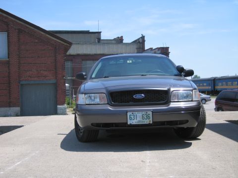 2001 Ford Crown Victoria - A gray 2001 Ford Crown Victoria is parked in front of a brick building on a sunny day.