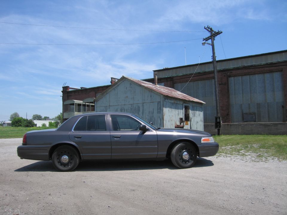 Gray 2001 Ford Crown Victoria parked on a gravel lot, side view