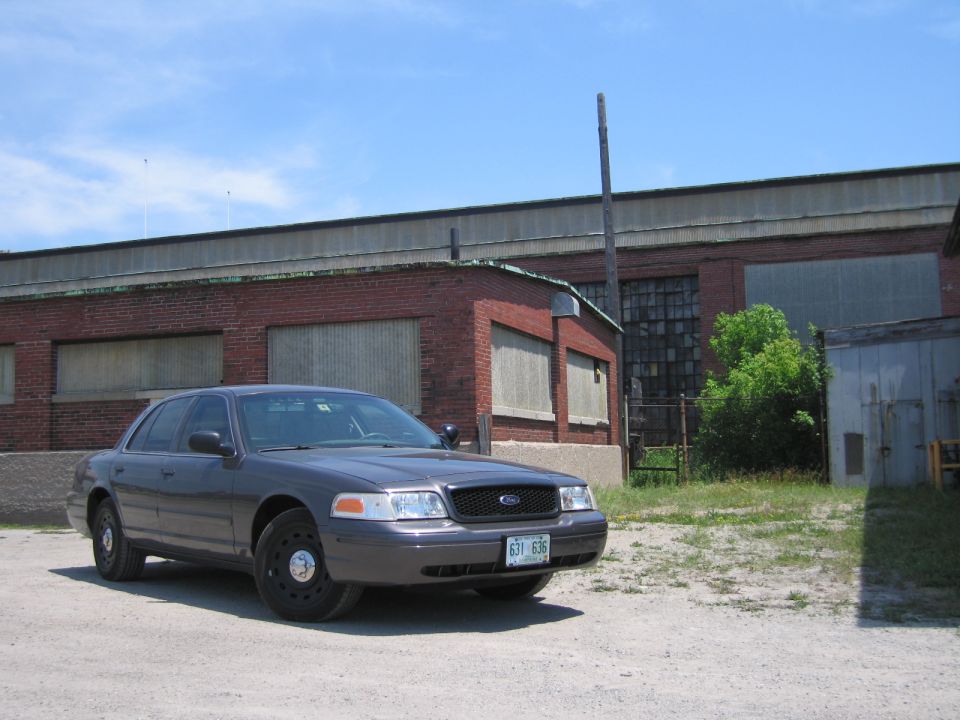 Gray Ford Crown Victoria police car parked in front of a brick building