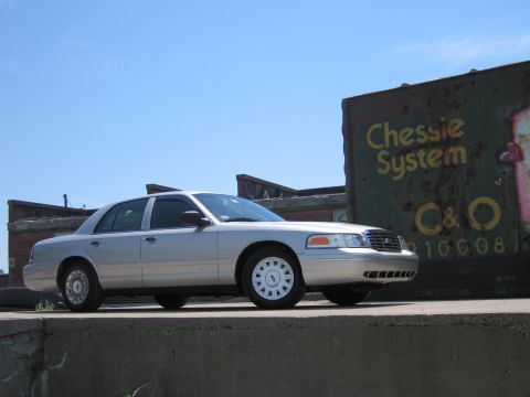 2001 Ford Crown Victoria - A silver 2001 Ford Crown Victoria is parked outdoors next to a train car with 'Chessie System' visible.