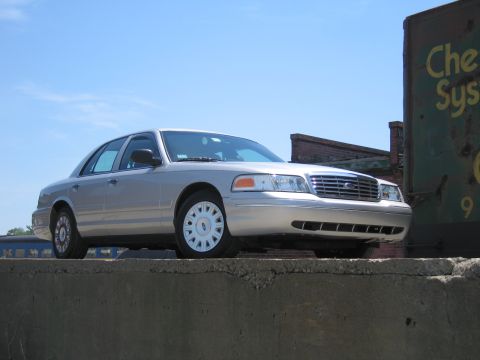 2001 Ford Crown Victoria - Silver 2001 Ford Crown Victoria parked on a concrete ledge with a train car in the background.