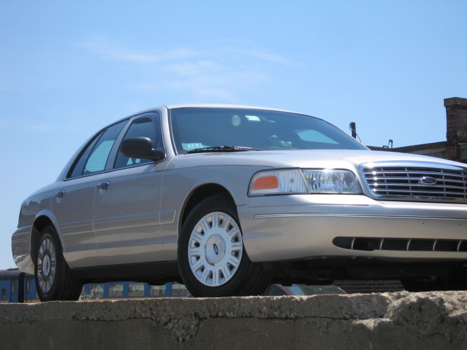 Silver 2001 Ford Crown Victoria sedan parked on a concrete ledge, viewed from the front right
