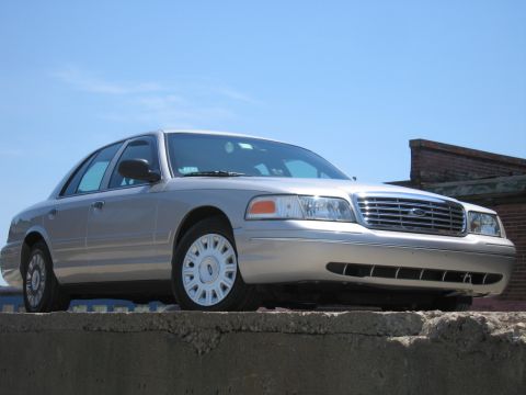 2001 Ford Crown Victoria - A silver 2001 Ford Crown Victoria is parked on a concrete ledge under a clear blue sky.