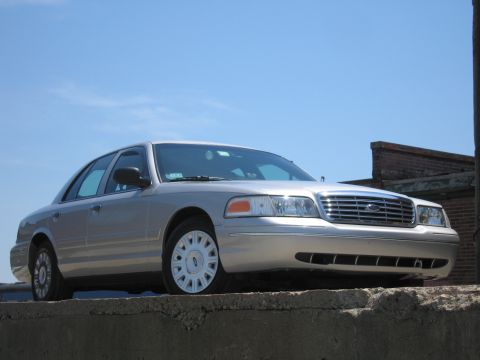 2001 Ford Crown Victoria - Silver 2001 Ford Crown Victoria parked on a concrete ledge under a clear blue sky.
