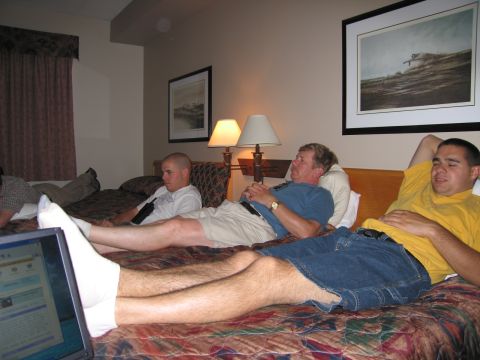 2001 Ford Crown Victoria - Three men are seen relaxing on beds in a hotel room, with a laptop in the foreground.