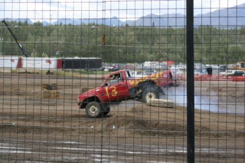 1975 Toyota Land Cruiser - A modified red pickup truck with large tires is seen in a dirt arena, possibly during a demolition derby or monster truck event.