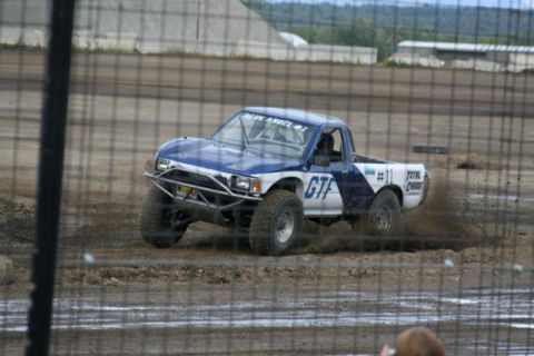 1975 Toyota Land Cruiser - This modified Toyota pickup truck competes on a dirt track, kicking up mud as it races.