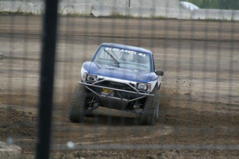 1975 Toyota Land Cruiser - Modified Toyota truck competes on a dirt track, kicking up dust as it turns.