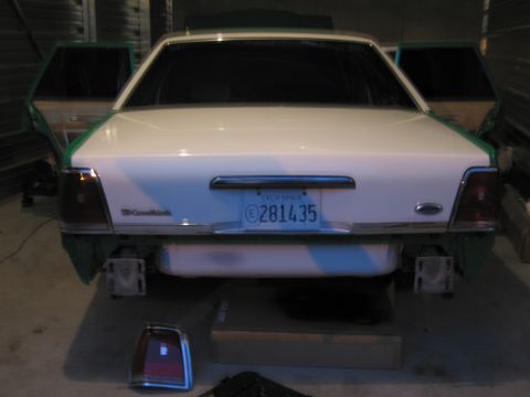 1991 Ford LTD Crown Victoria - The rear of a 1991 Ford Crown Victoria is shown with its doors open, indicating it is in a workshop or garage.