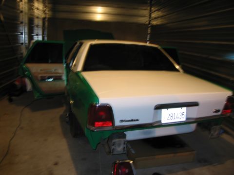 1991 Ford LTD Crown Victoria - A two-tone green and white Ford Crown Victoria is parked inside a garage with its doors and hood open.