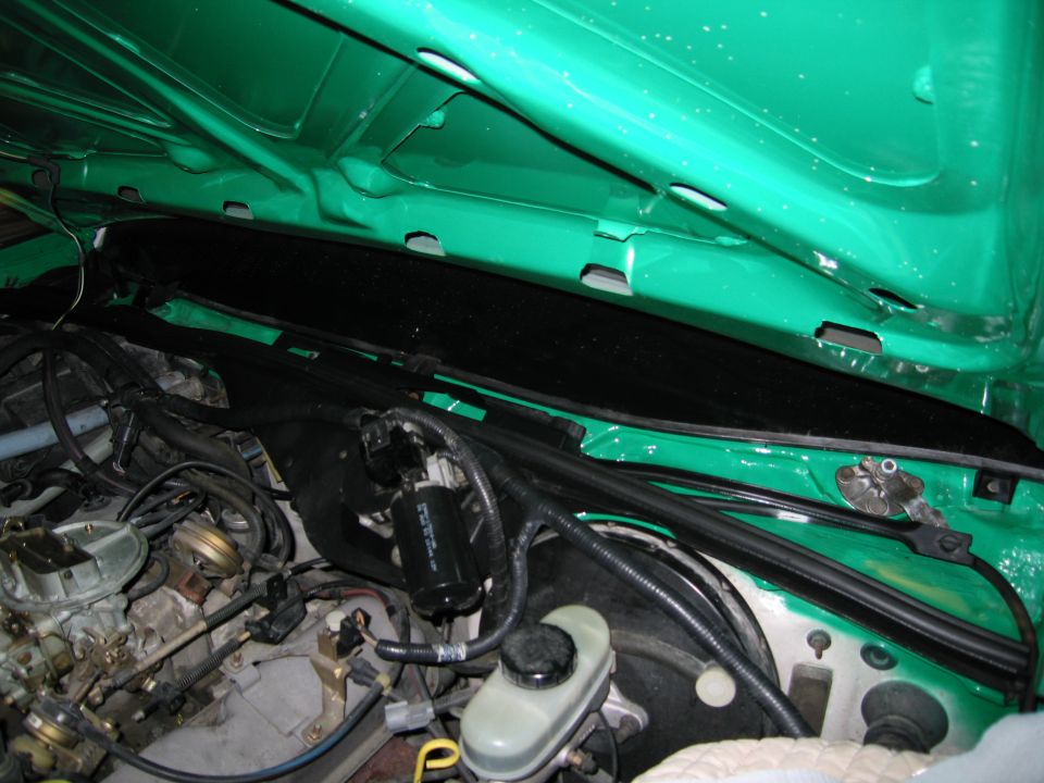 Engine bay with green painted hood interior, showing carburetor, brake fluid reservoir, and wiring