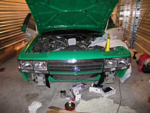 1991 Ford LTD Crown Victoria - Front view of a green 1991 Ford Crown Victoria LTD in a garage with the hood up and bumper removed.