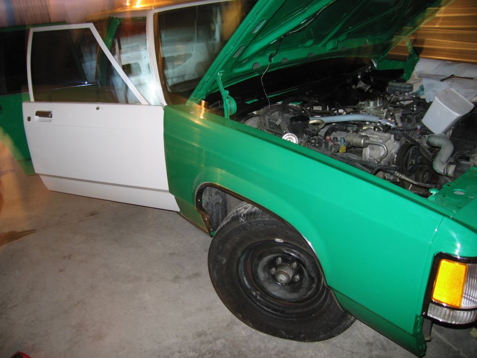 Green and white car, front view, hood open showing engine