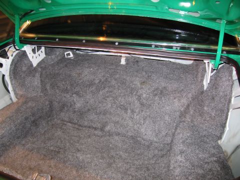 1991 Ford LTD Crown Victoria - The interior of a car trunk, showing the carpeted floor and sides, with green painted metal.