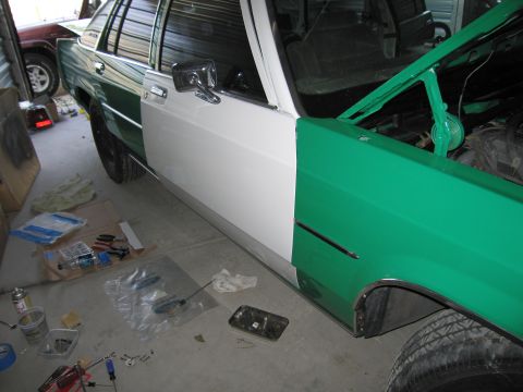 1991 Ford LTD Crown Victoria - A car undergoing repairs, with its hood open and parts laid out on the garage floor.