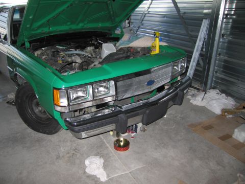 1991 Ford LTD Crown Victoria - Front view of a green 1991 Ford Crown Victoria LTD with its hood open, parked indoors.