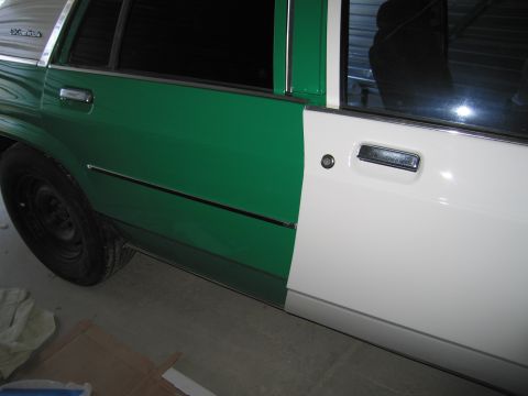 1991 Ford LTD Crown Victoria - The side of a 1991 Ford Crown Victoria LTD shows a two-tone paint scheme with green on the rear section and white on the front door.
