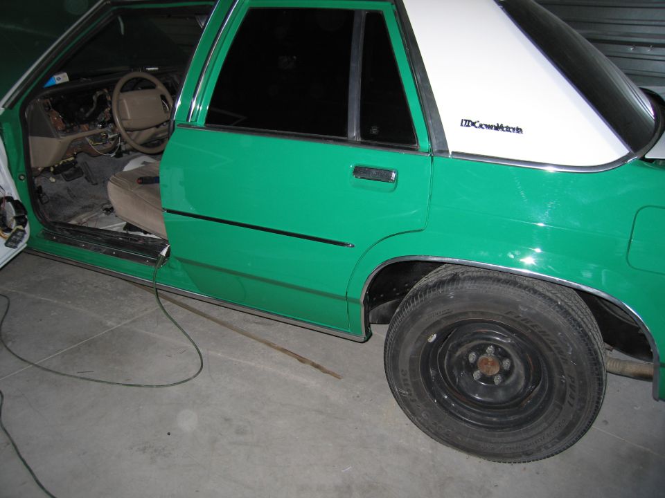 Green 1991 Ford Crown Victoria LTD with interior disassembled, showing dashboard and driver's seat. Rear passenger door and wheel are visible