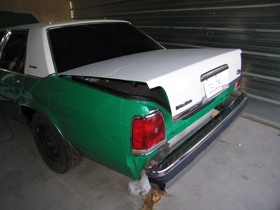 Rear of a green and white Ford Crown Victoria with trunk open. License plate area is visible