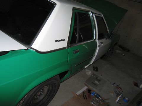1991 Ford LTD Crown Victoria - A two-tone green and white 1991 Ford Crown Victoria LTD sedan is parked in a garage with its hood open.