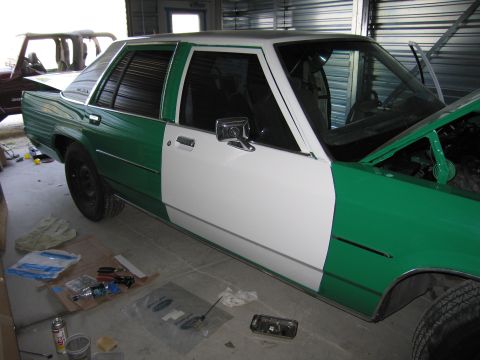 1991 Ford LTD Crown Victoria - A 1991 Ford Crown Victoria LTD is shown in a garage, with one side painted white and the other green, indicating ongoing bodywork.