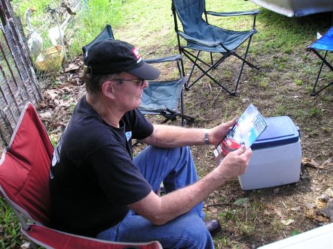 2009 Ford Mustang - A man sits outdoors reading a magazine a red car on its cover.
