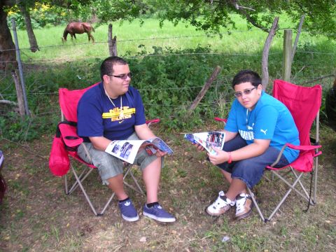 2009 Ford Mustang - Two people relax and read magazines outdoors, with a horse visible in the background field.