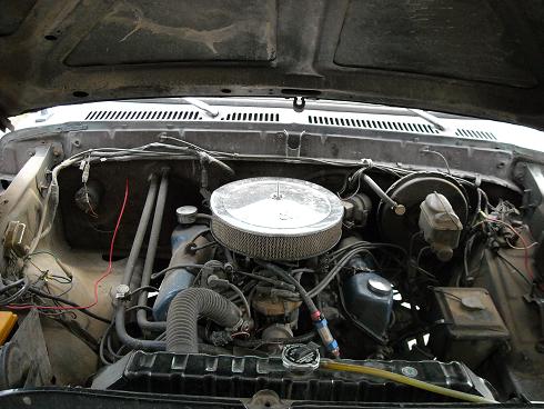 Engine bay with air cleaner, hoses, and brake booster visible