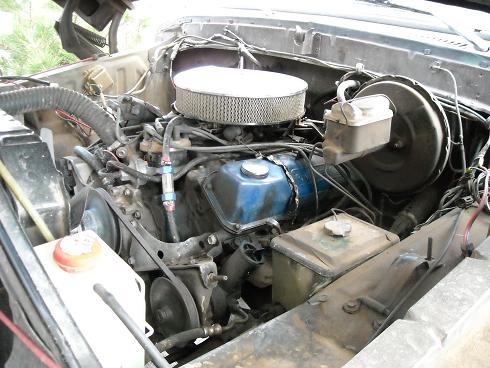 Engine bay with V8 engine, air cleaner, brake booster, and fluid reservoirs. Some hoses and wiring are visible